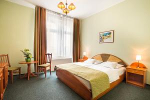 Baross City Hotel - Budapest في بودابست: غرفة فندقية بسرير وطاولة وكراسي