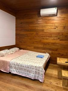 a bedroom with a bed and a fan and wooden walls at Motel Tuệ Nhi II in Plei Kơtêng