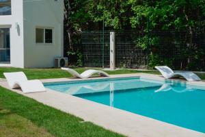 a swimming pool with two white chairs next to it at T Loft in Playa Hermosa