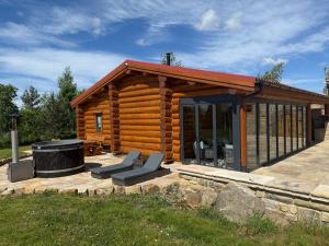 a log cabin with a grill and chairs in front of it at The Estate, Luxury Spacious Family Stay with 3 Hot Tubs, Scenic Views Sleeps 16 near Durham & Bishop Auckland in Durham