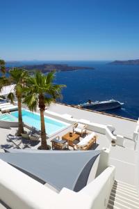 Blick auf einen Pool mit Liegestühlen und Palmen in der Unterkunft Villa Aura in Firostefani