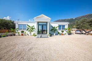 a white house with palm trees in a driveway at Pegasus-In Hotel Borsh in Borsh