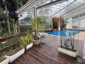 a glass greenhouse with plants and a swimming pool at Chácara Fontenele in Mairiporã
