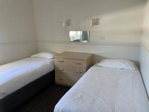 a bedroom with two beds and a dresser and a mirror at Perisher Manor Hotel in Perisher Valley