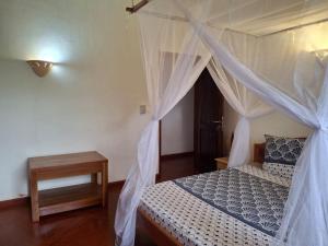 a bedroom with a canopy bed and a table at Résidences-Bel-R in Nosy Be