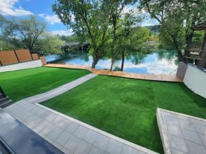 ein Garten mit grünem Gras und einem Teich in der Unterkunft La Villa Luxury Home Bihac in Bihać