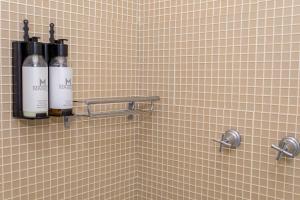 a bathroom with two bottles of wine on a tiled wall at Maison Hotel - Tangará da Serra in Tangara da Serra +92 photos
