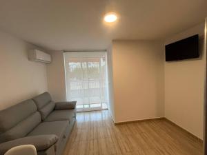a living room with a couch and a television at APCOSTAS Palmavera Playa de la Conxa in Oropesa del Mar