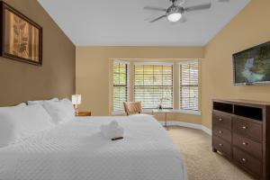 a bedroom with a white bed and a dresser at 4BR Disney Family Townhouse Resort in Orlando - with Resort Pool, Gym, Games, & Jacuzzi in Orlando +91 photos