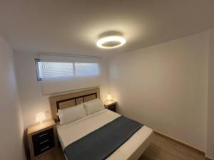 a bedroom with a bed with two night stands and a window at APCOSTAS Palmavera Playa de la Conxa in Oropesa del Mar