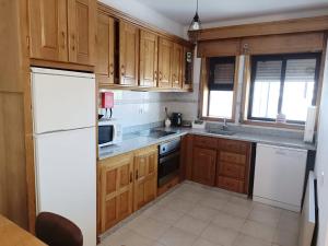 una cucina con mobili in legno e un frigorifero bianco di A&B Apartments - Banrezes a Macedo de Cavaleiros