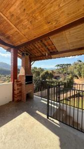 an outdoor patio with a brick fireplace and a wooden roof at Recanto da Paz - Monte Verde in Monte Verde