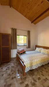 a bedroom with a large bed and a window at Recanto da Paz - Monte Verde in Monte Verde