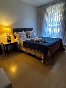 a bedroom with a bed with a blue blanket and a window at Chalé Mosel in Petrópolis +5 photos