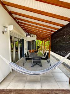 a hammock on a patio with a table and chairs at Villa du FORT in Goyave