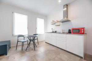 a kitchen with white cabinets and a table with a red microwave at Modern Flat with Garden and parking in Quiet Area in Padova