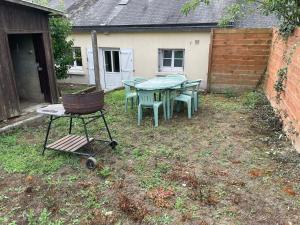 un cortile con un tavolo e delle sedie e una pentola su un carrello di Gite proche Chateau-gontier a Marigné-Peuton