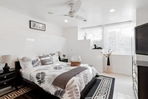 a white bedroom with a bed and a flat screen tv at Quiet Home with Spectacular Scenic Mountain Views near Universal Studios Hollywood in Los Angeles