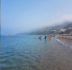 a group of people standing in the water at the beach at Vue Mer Tamernout in Aouchtame