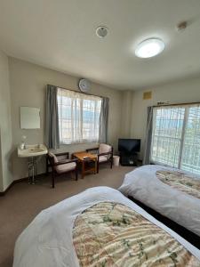 a hotel room with two beds and a desk at トガリハイランド白樺 in Iiyama