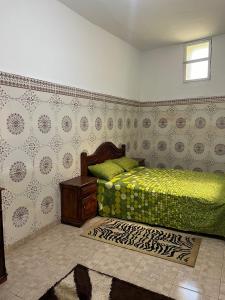 a bedroom with a bed with green sheets and a table at Maison Ghali in Safi