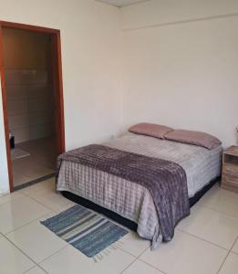 a bedroom with a bed and a bathroom at Casa Vilarejo in Morretes