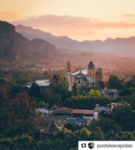 a large building in a town with mountains in the background at Hostal Casa Petricor 