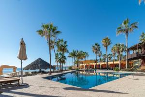 ein Swimmingpool mit Palmen und einem Sonnenschirm in der Unterkunft Hotel Playa Del Sol in Los Barriles