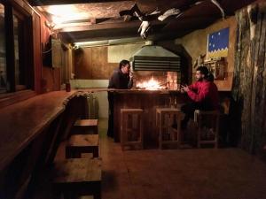 two people sitting at a bar with a fire at Hostel Patagonia Backpackers in Puerto Natales