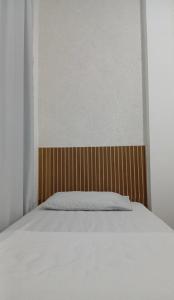 a bed with a wooden headboard in a room at Apartamento em Itapuã in Vila Velha