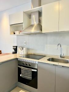 a kitchen with white cabinets and a stove and a sink at Edificio Ventura Carmelitas in Asuncion