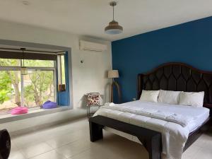 a bedroom with a bed with a blue wall and a window at Casa La Perla del Sur Confort y calidez en todos sus espacios in Ticul +44 photos