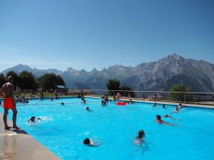 a group of people swimming in a swimming pool at Comfy apartment with terrace in Nendaz