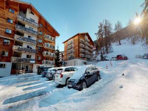 a parking lot with cars parked in the snow at Comfy apartment with terrace in Nendaz