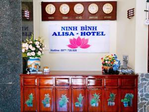 a wooden cabinet in a room with clocks on the wall at Ninh Binh Alisa Hotel in Ninh Binh