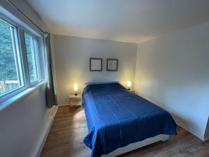 een slaapkamer met een blauw bed en 2 lampen bij Le Refuge des Eaux Vives in La Macaza