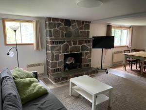 een woonkamer met een stenen open haard en een bank bij Le Refuge des Eaux Vives in La Macaza