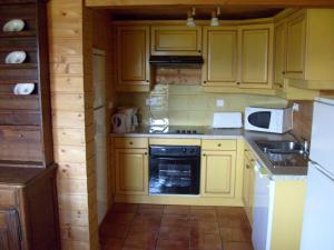 a kitchen with yellow cabinets and a stove top oven at Rustic Chalet for Families in Le Ménil