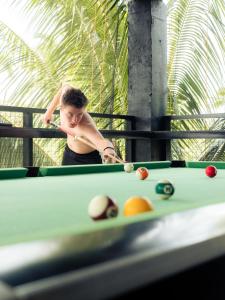 a man playing billiard with a cue in a pool table at Surfer's Hostel Siargao in General Luna