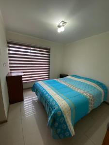 a bedroom with a bed with a blue comforter and a window at Casa lago rapel in Lago Rapel +16 photos