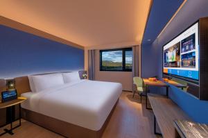 ein Hotelzimmer mit einem Bett und einem Flachbildfernseher in der Unterkunft Orange Beijing Yanqing Badaling Great Wall Hotel in Xibozi