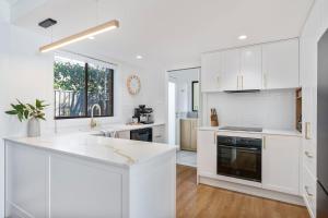 a kitchen with white cabinets and a counter top at Lucille in Mollymook