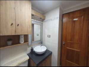 ein Badezimmer mit Waschbecken und Holztür in der Unterkunft Apartamento cercano a Termas de Chillán in Las Trancas