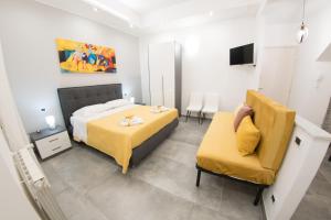 a bedroom with a bed and a yellow chair at Affittacamere SANT'ANNA in Caltagirone