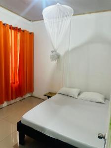 a bedroom with a white bed with orange curtains at Casa Teo número 2 in Puerto Viejo