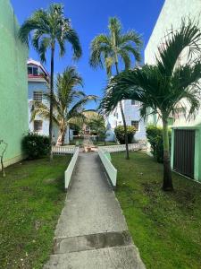 a walkway in front of a building with palm trees at Studio apartment in the heart of Cole Bay in Koolbaai