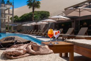 Zwei Cocktails auf einem Tisch neben einem Swimmingpool in der Unterkunft Senoma Hotel - Adults only in Ica