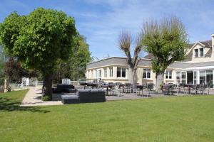 a white house with tables and chairs in a yard at Le Quincangrogne in Dampmart