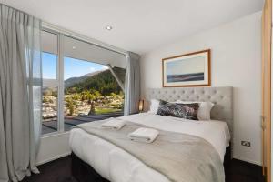 a bedroom with a large bed with a large window at Central Sunset Charm in Queenstown