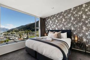 a bedroom with a large bed and a large window at Central Sunset Charm in Queenstown +30 photos